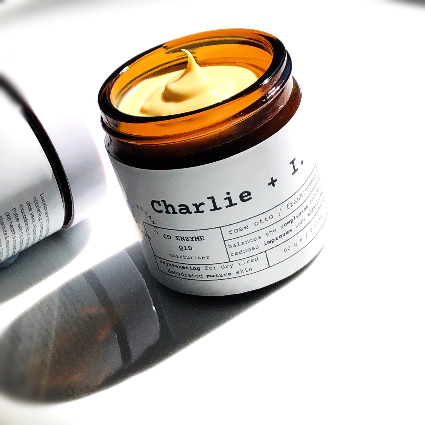 A jar of Rose Frankincense Moisturiser with Co Enzyme Q10 Carrot Seed by Charlie +伊, showing the product name and some descriptive text on the label.